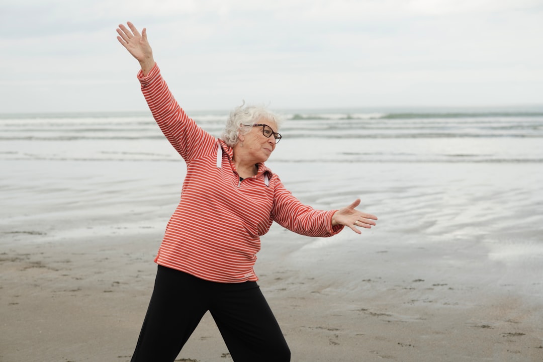 elderly woman doing balance exercise yoga mat indoors